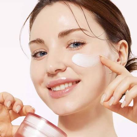 Mulher aplicando creme facial na bochecha