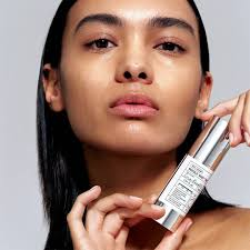 Mulher segurando sérum facial branco perto do rosto